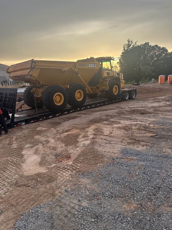 Yellow Bell articulated dump truck on trailer at sunset