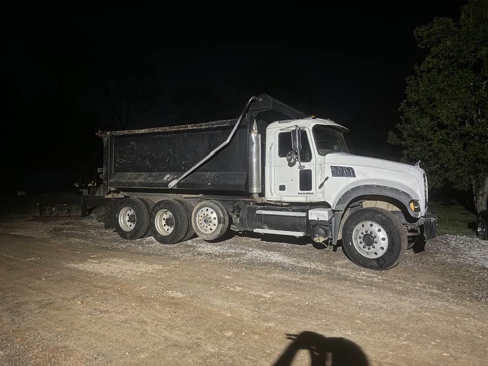 White Mack tri-axle dump truck at night